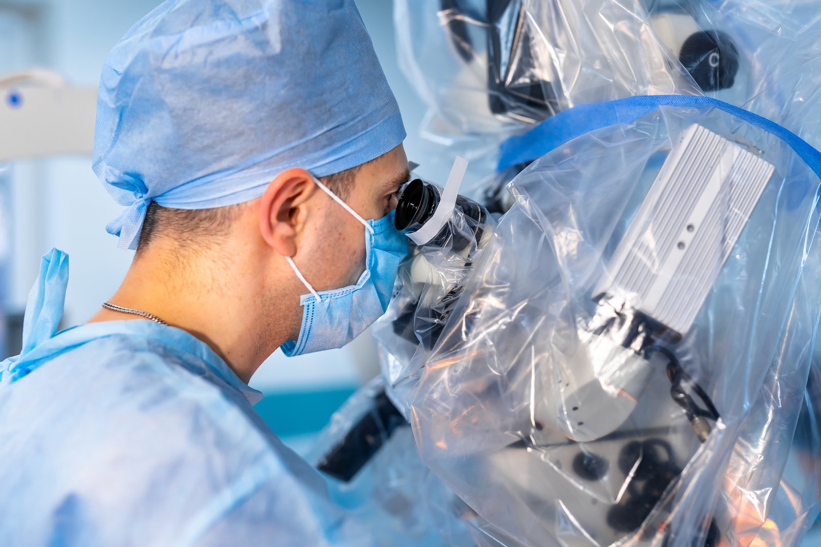 A surgeon looking through an operating microscope during surgery