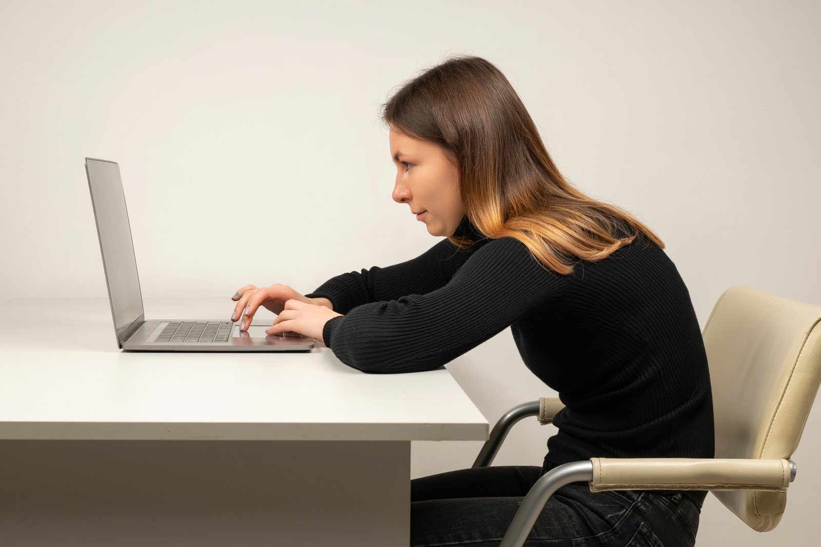 A woman slouching while working on a laptop